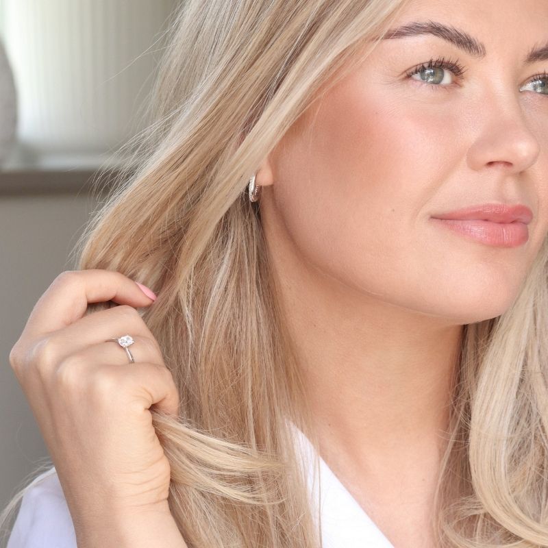 Kvinna med diamant hoops och solitärring i vitguld.