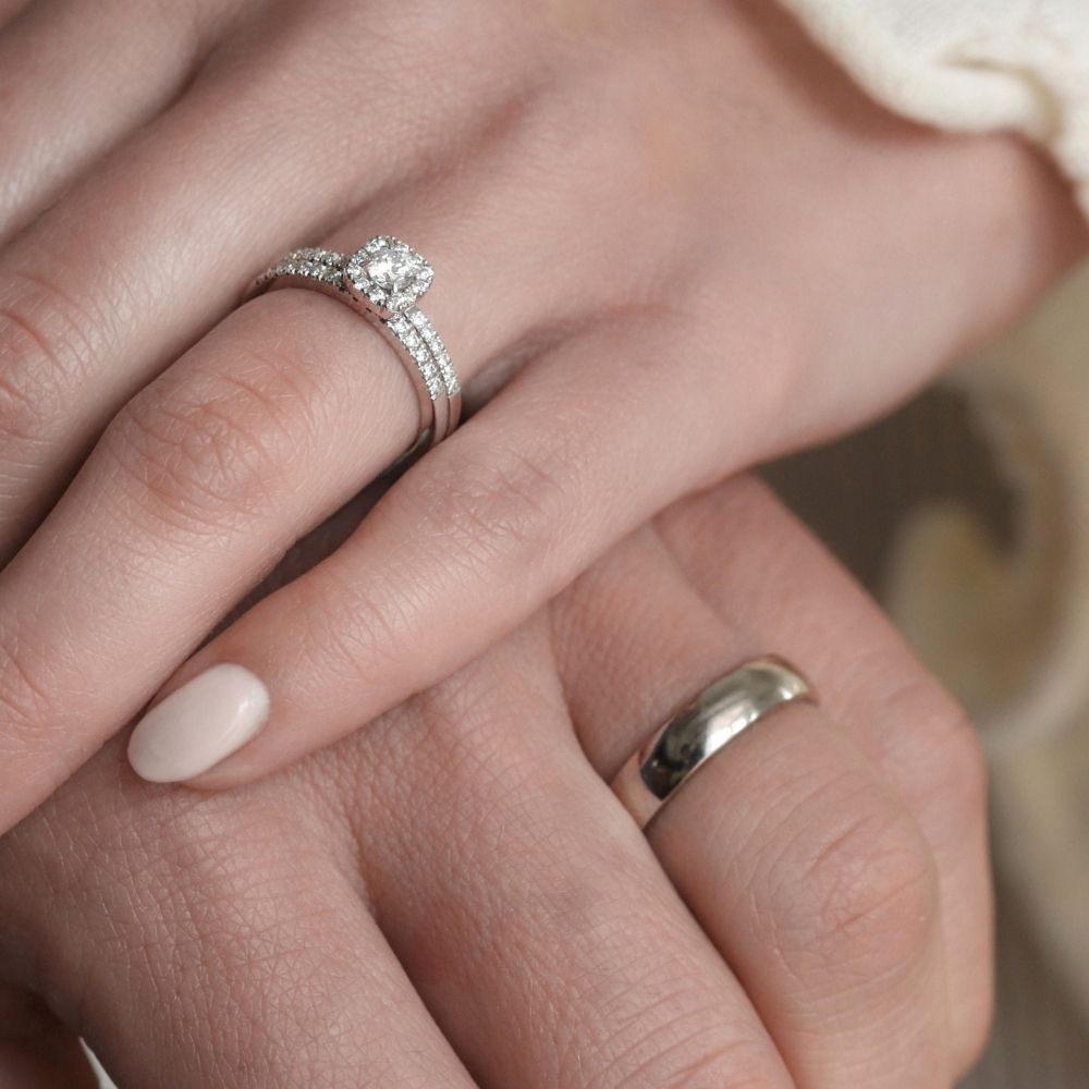 Närbild på ett ett pars händer som precis gift sig. Vigselringar i vitguld och med diamant från Schalins