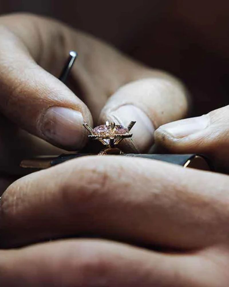 Närbild på en guldsmeds händer i arbete med en diamantring