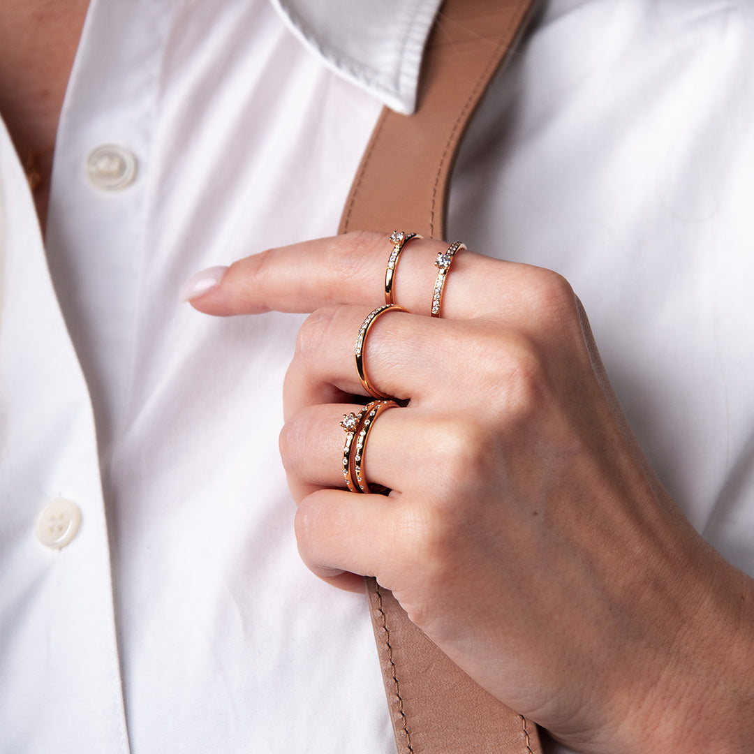 Guld och diamantringar på handmodell klädd i vit blus.