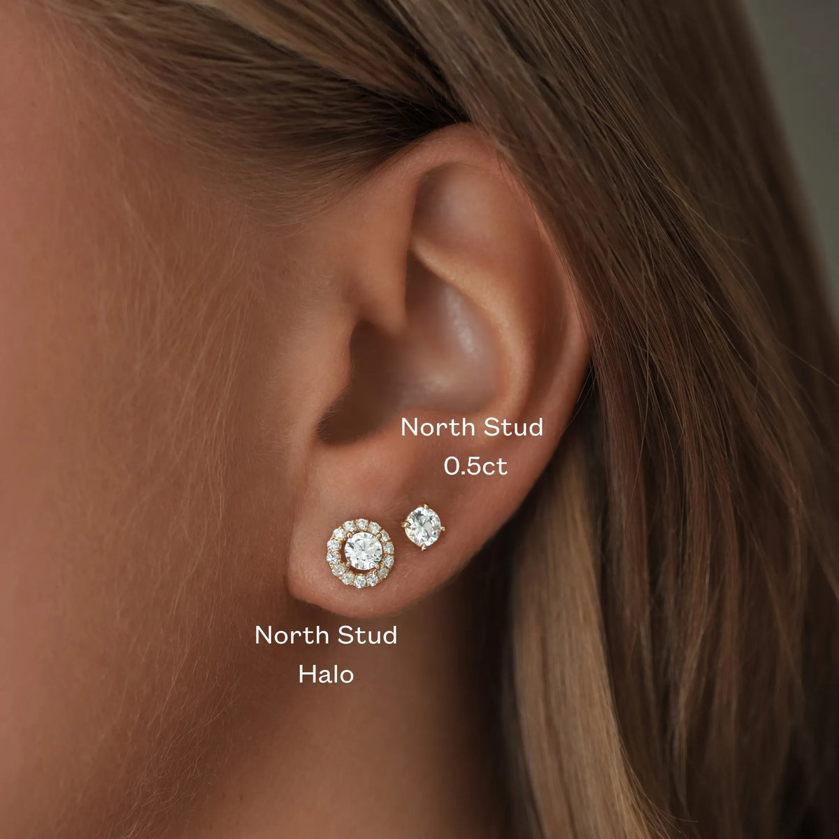 Närbild av ett öra med North Stud Halo i rödguld, med en rund diamant omgiven av mindre diamanter, bredvid en North Stud på 0,5 ct från Schalins.