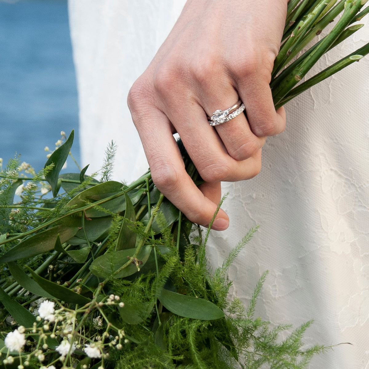 Eterna trestensring och helallians i vitguld med diamanter, hand håller bukett