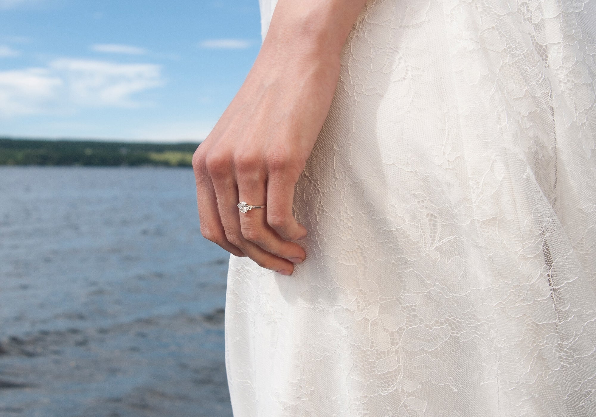 Hand med Schalins Eterna trestensring i guld med diamanter vid vatten