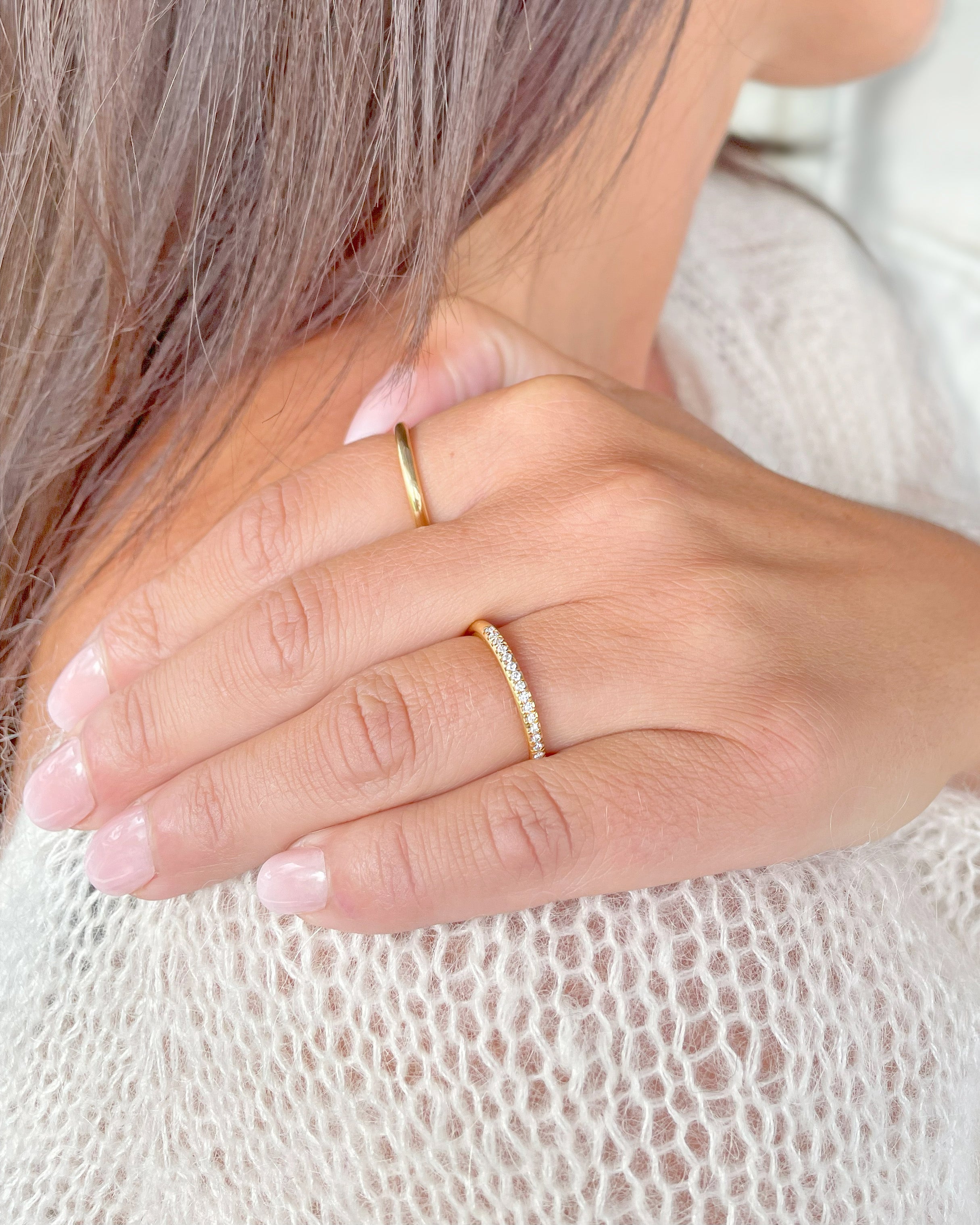 Närbild på hand med slät guldring och diamantallians i guld