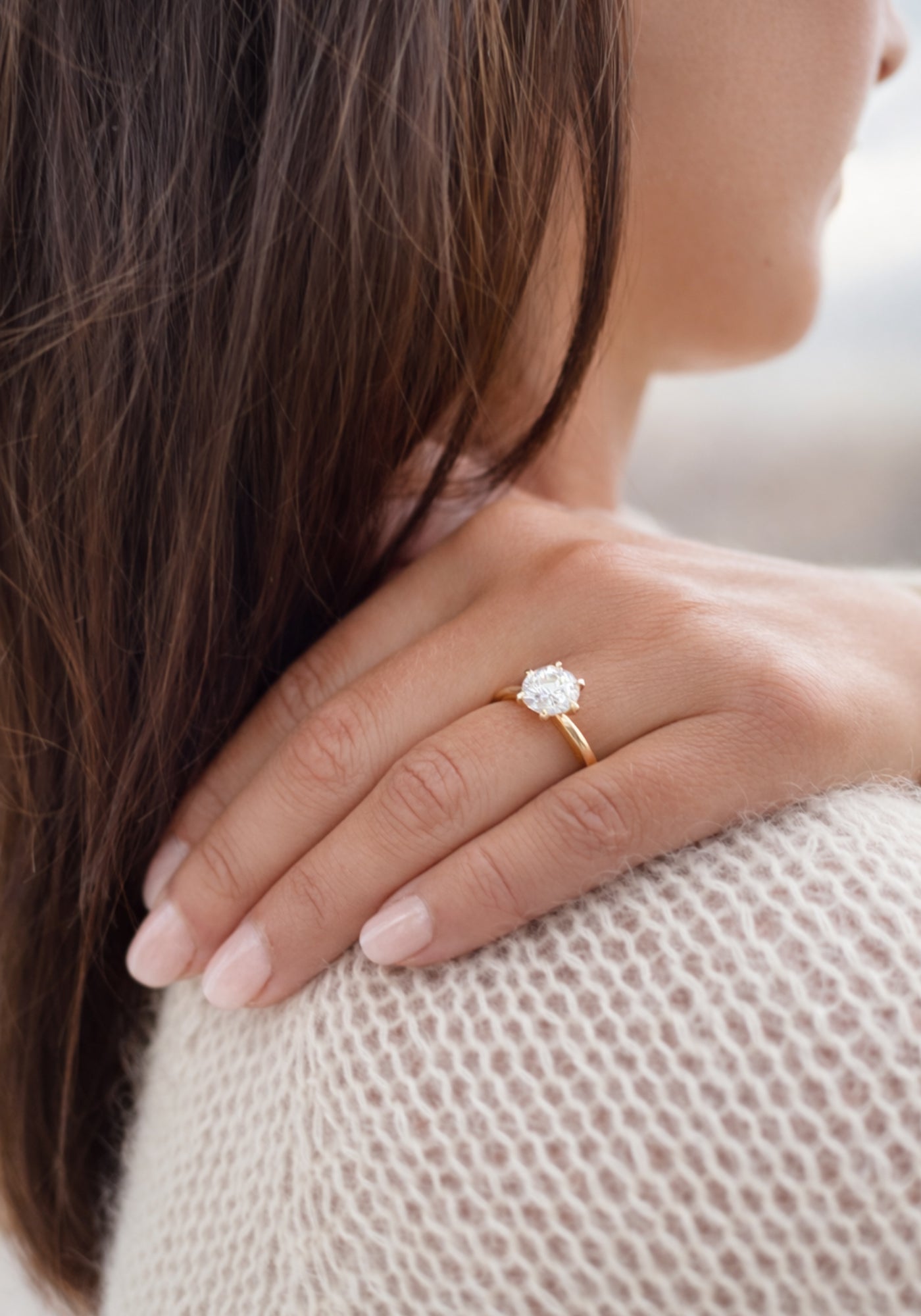 Förlovningsring i guld med labgrown diamant från Schalins North kollektion på hand över axel