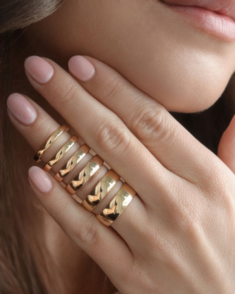 Närbils på en hand med flera olika släta ringar med olika ringbredd. 