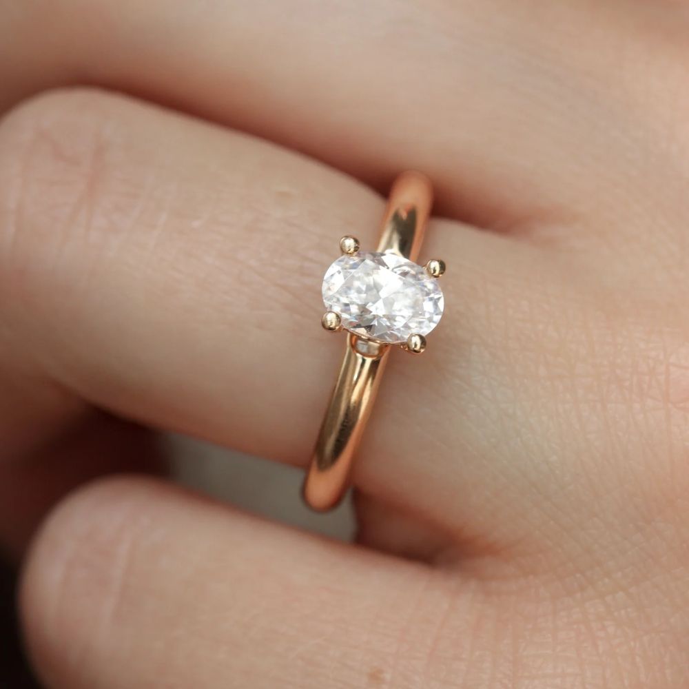 ärbild på en ring i metall rödguld och oval diamant