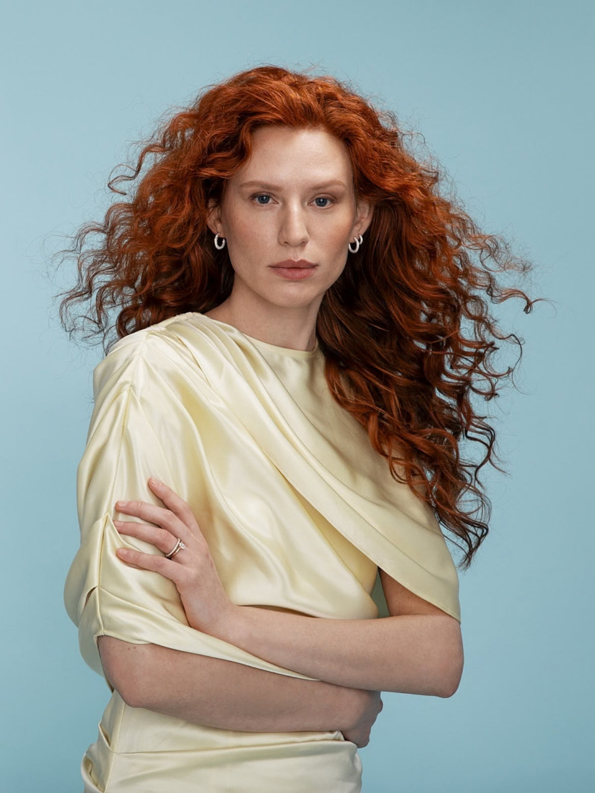 Kvinna bär Aure pavé och solitärring samt hoops-örhängen med diamanter från Schalins i ett elegant porträtt