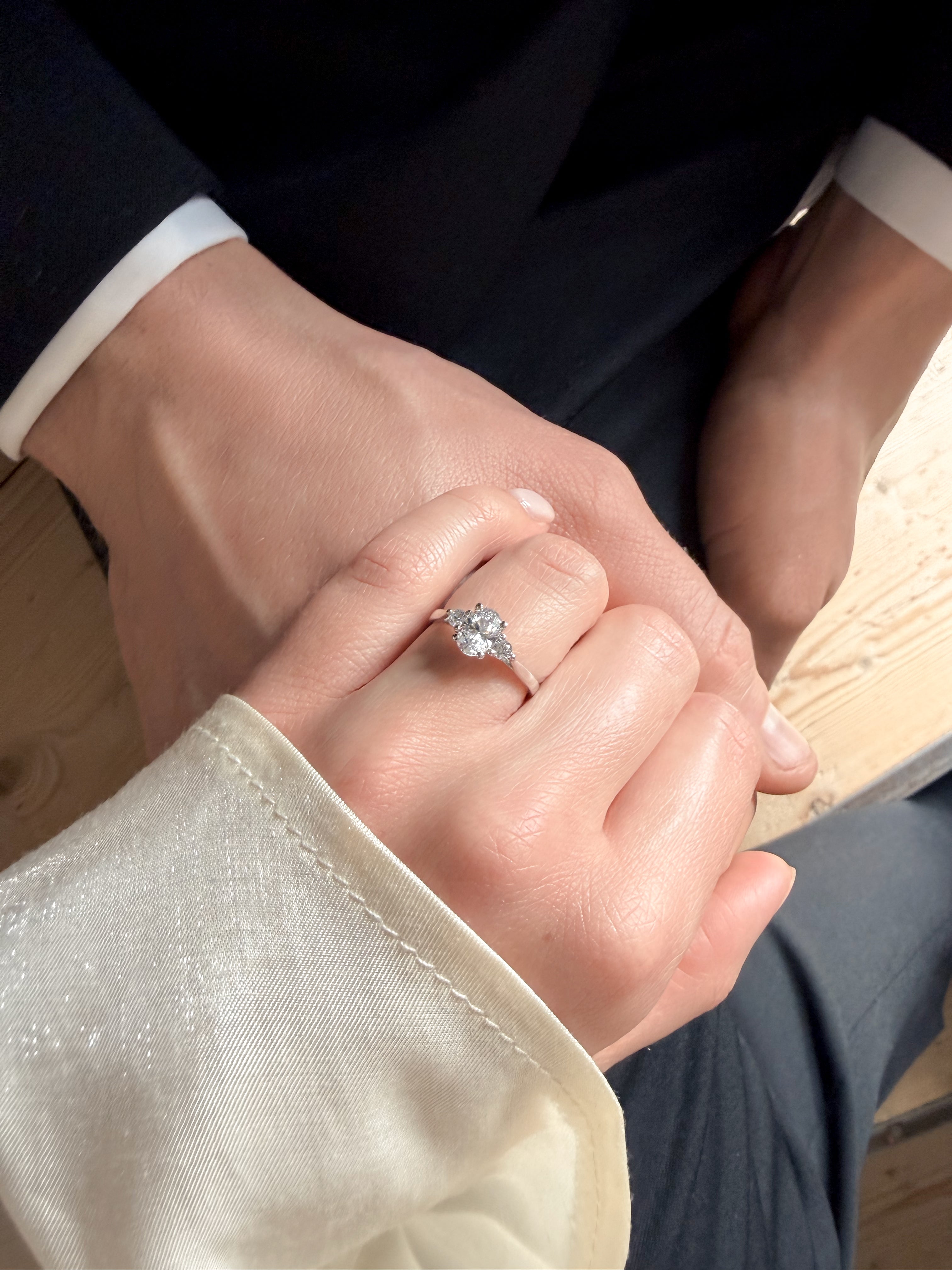 Detaljbild av Eterna trestensring i vitguld med tre briljantslipade diamanter på sammanflätade händer