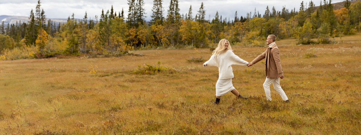 Förlovningspar går genom skog och äng hand i hand 