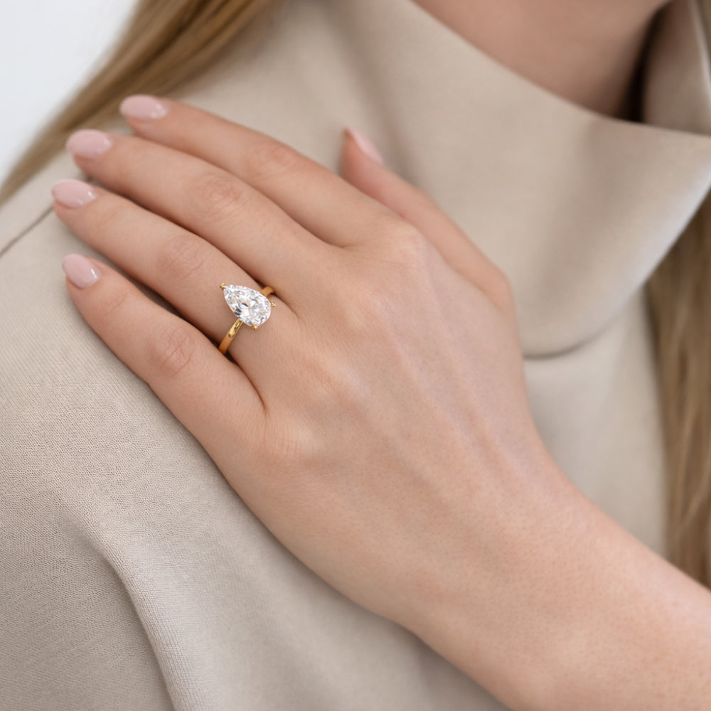 Närbild på North diamantring i guld med lab grown pear cut diamant på hand från Schalins