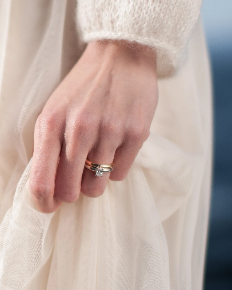 Närbild på hand med ringstack i vitguld med förlovningsring och vigselring med diamanter