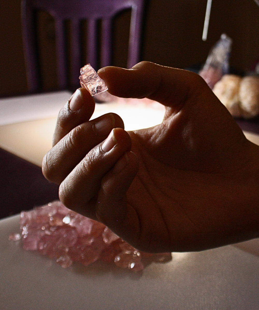 Hand som håller en rå rosa morganit -ädelsten i naturlig form från Schalins