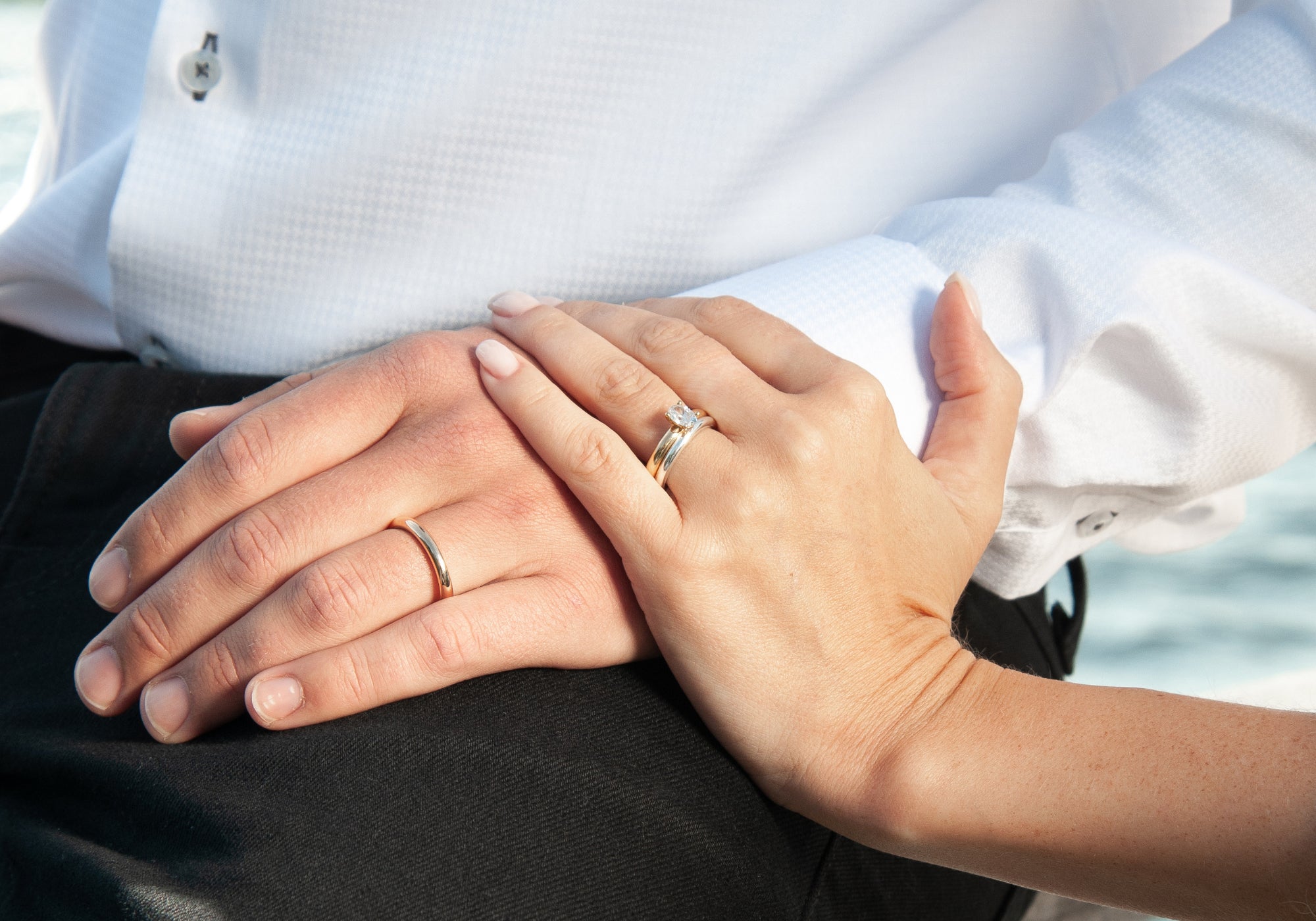 Schalins Aure förlovnings- och vigselringar i guld på händer i nära detalj