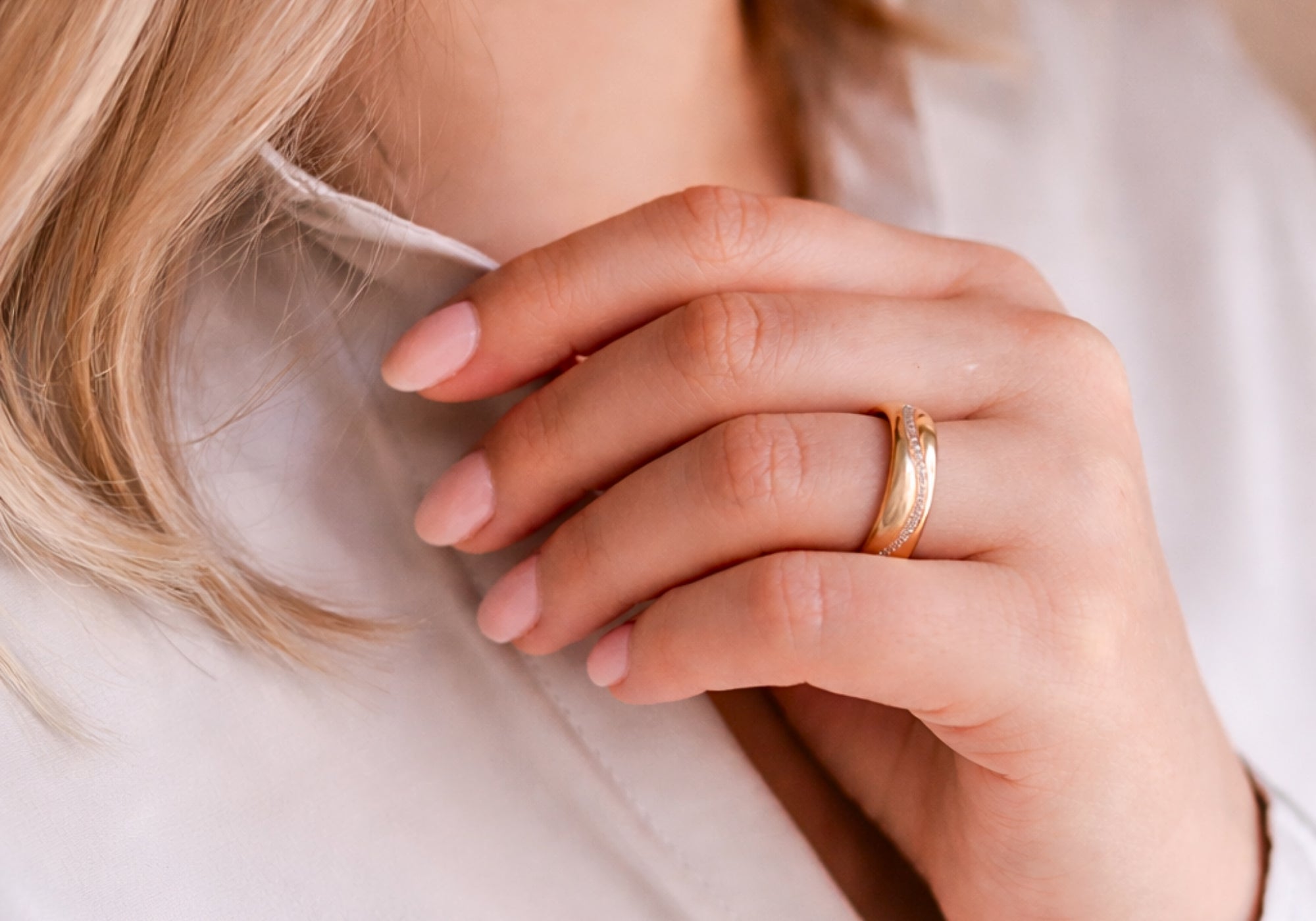 Vigselring i guld från Schalins Sign of Love kollektion på hand i nära detalj